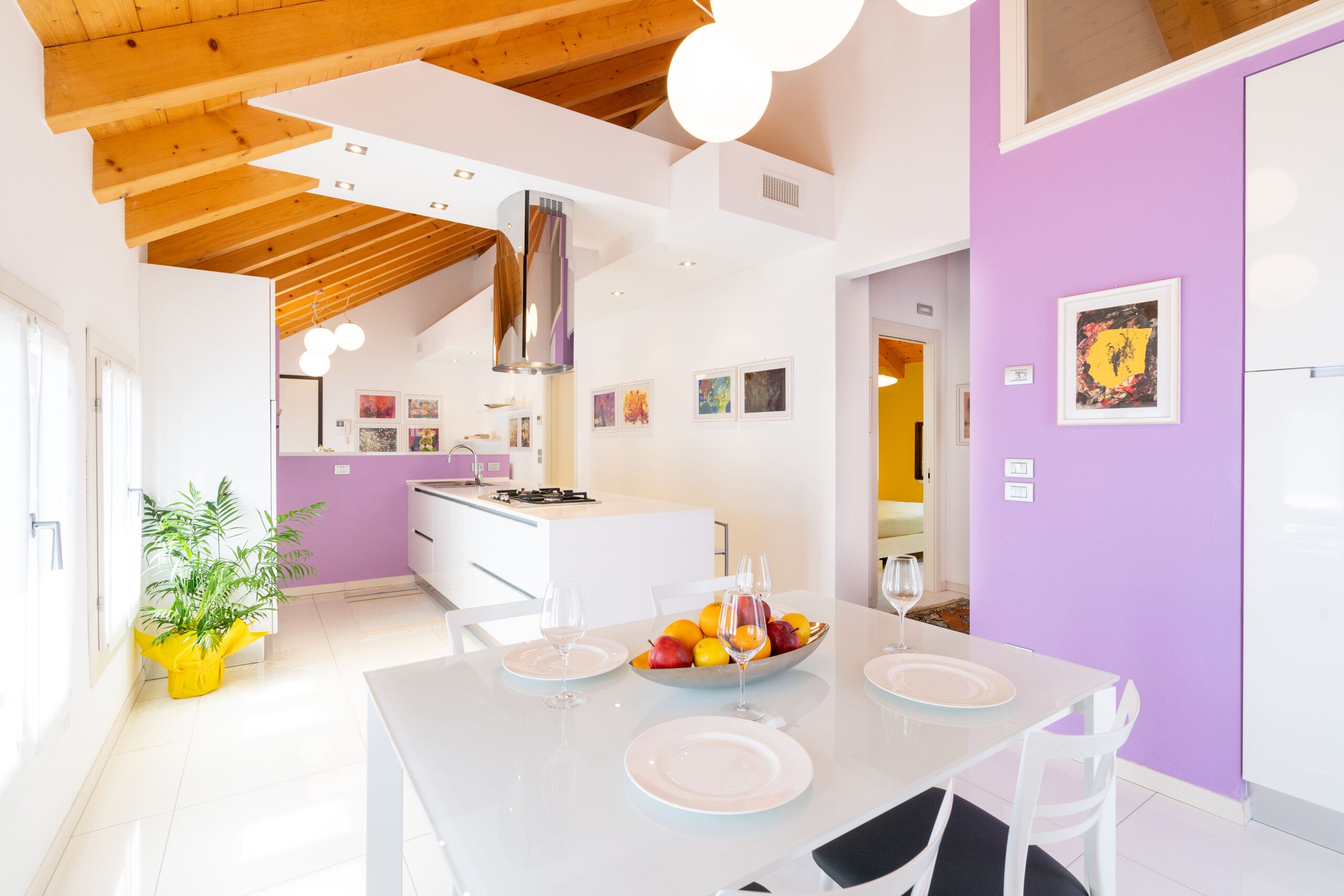 Cucina e zona pranzo di un appartamento di Antichi Giardini, con travi a vista e pareti lilla